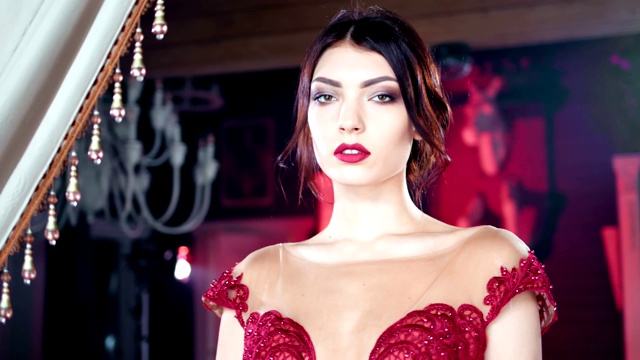 时尚的黑发女人与晚妆和红色的嘴唇摆姿势在奢侈的背景视频素材