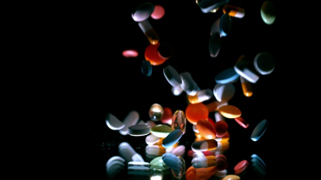 SLO MO彩色药丸落在闪亮的表面视频素材