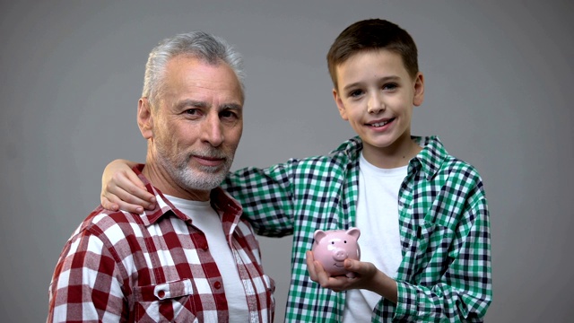 老人把硬币放进小男孩的小猪存钱罐里，为将来储蓄，存钱视频素材