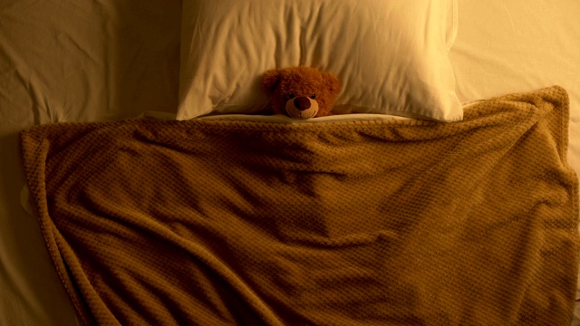泰迪熊躺在床上盖着玩具毯子，回忆着童年，天真烂漫视频素材