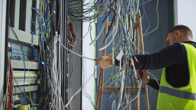 男性电工安装电缆和电线在一个新的电气外壳视频下载