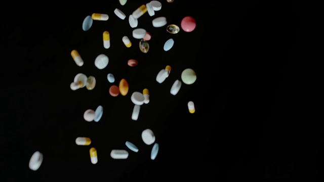 药丸和胶囊落在黑色的背景视频素材