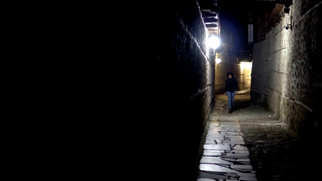 孤独的女人晚上走在后街古老的石头铺砌的小巷里视频素材
