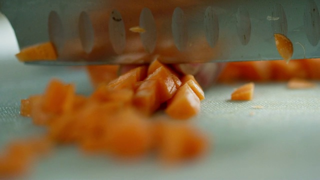 一位年长的白人妇女用菜刀在切菜板上切胡萝卜视频素材