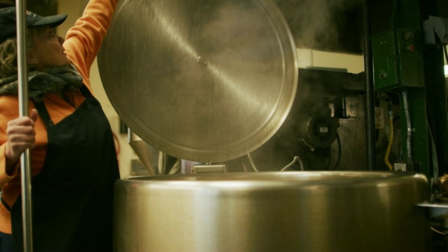 一名六十多岁的白人妇女在商业厨房/制造设施中打开一个大型金属储存罐的盖子视频素材