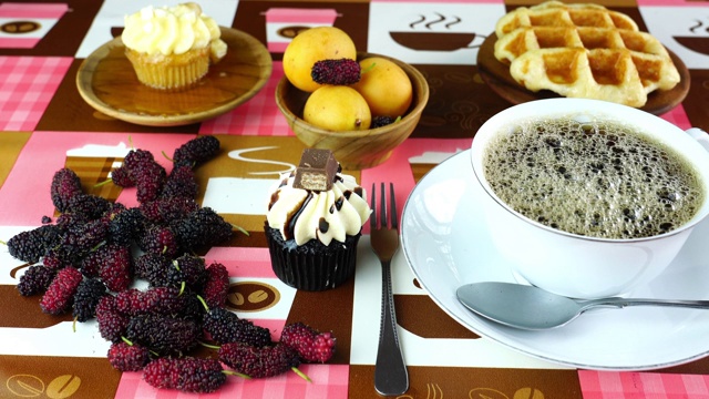 将黑咖啡倒入桌上的白色杯子里，配上巧克力蛋糕华夫饼和各种水果视频素材