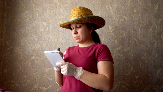 一位头戴牛仔帽、身穿勃艮第t恤的女士在笔记本上做笔记视频下载