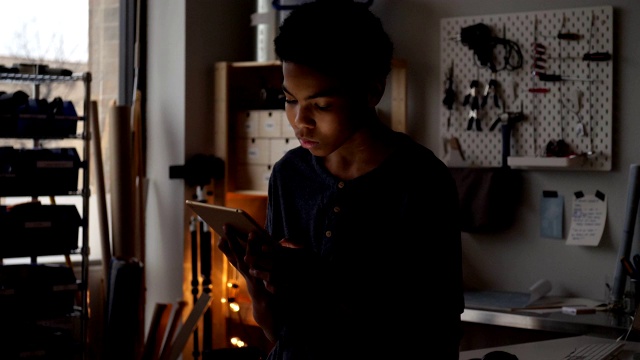 一个十几岁的男孩在家里用平板电脑玩游戏视频素材