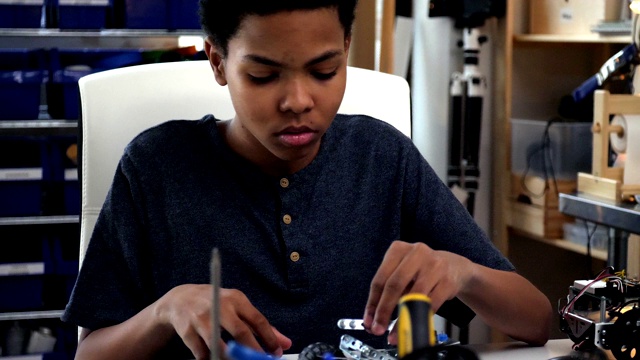 一个十几岁的男孩小心地组装机器人车视频素材