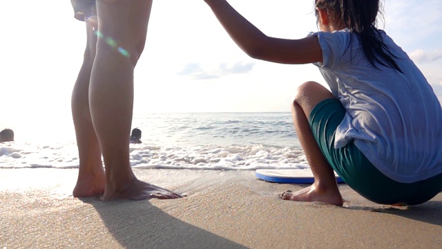 幸福的家庭，母亲和女儿在日落的海滩上，慢镜头视频素材