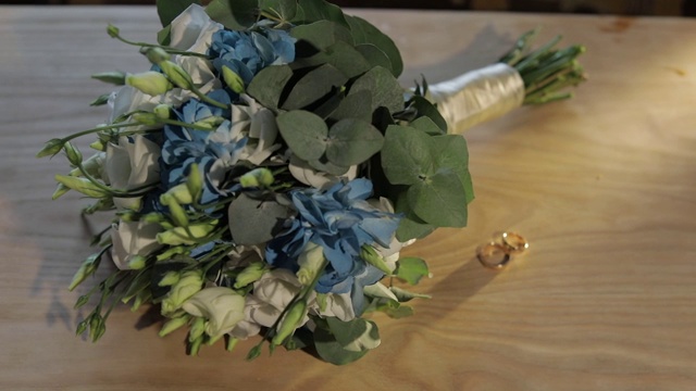 在木桌上，婚戒和漂亮的婚礼花束放在一起视频素材