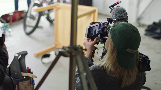 女电影摄影师蹲下与相机钻机和拍摄场景的电影设置。视频素材