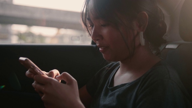 年轻女子玩在车里使用手机。视频素材