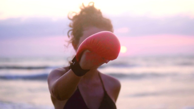 空手道运动女孩锻炼，在海边沙滩上训练空手道迎着夕阳，集中手套视频下载