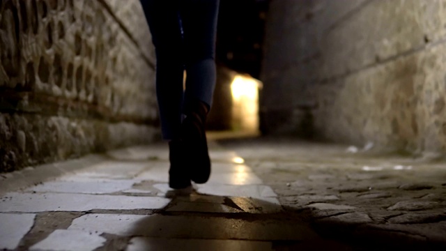 电影般的徒步行走的女人的脚在旧巷黑暗的街道石头路面上行走视频素材