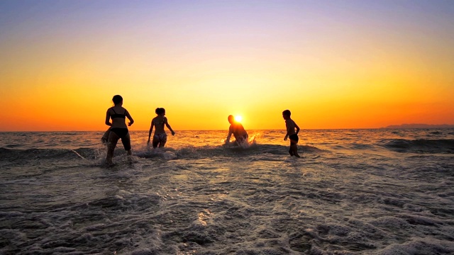 家庭成员在春天举行派对，在夏天的海滩日落上跳跃，电影的慢动作视频素材
