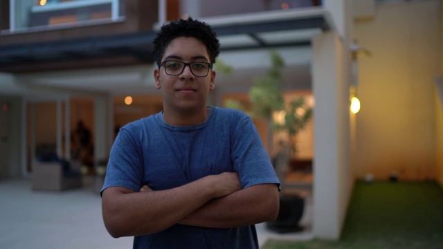 一个十几岁男孩在房子前面的肖像视频素材