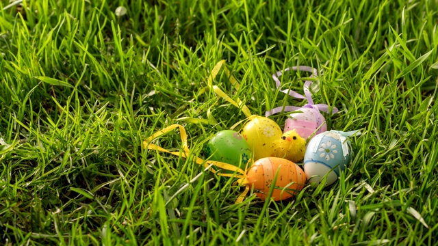 雪在绿色的草地上融化，草地上点缀着五颜六色的复活节彩蛋和小鸡视频素材