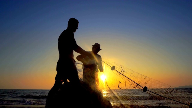 сУнрецогнизабле渔夫在海上撒网捕鱼ат日落，电影镜头视频素材