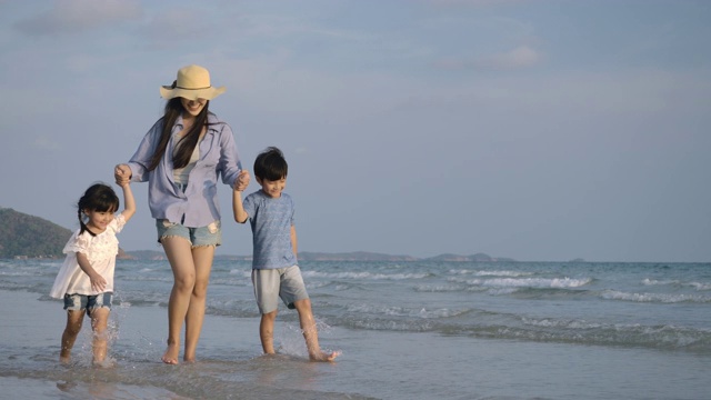 快乐的母亲和她的孩子享受和走在海滩上的暑假。缓慢的运动。家庭，假期和旅游的概念。视频素材