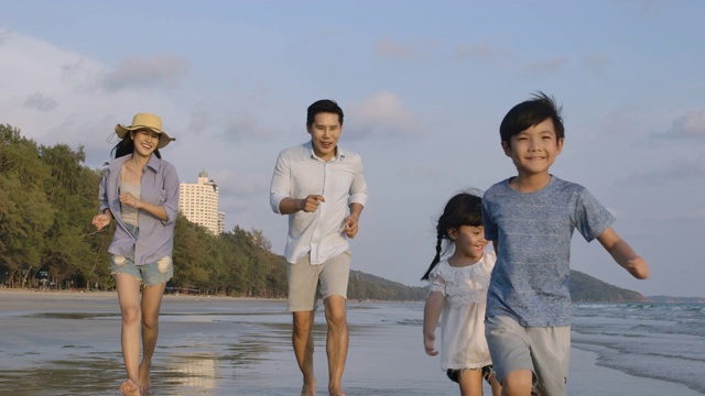 爸爸，妈妈和孩子们白天在海滩上跑步。缓慢的运动。家庭，假期和旅游的概念。视频素材