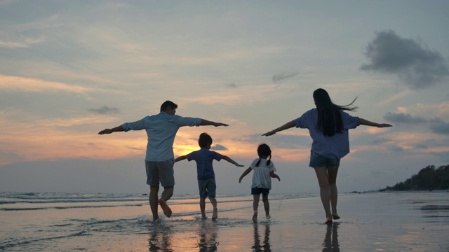 剪影快乐的亚洲家庭玩和有乐趣的海滩上日落。缓慢的运动。家庭、自由和旅行的概念。视频下载