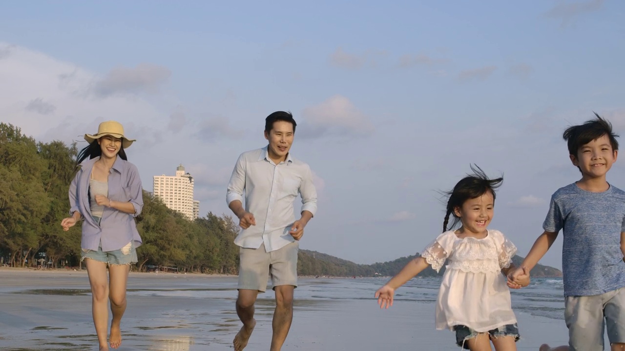 爸爸、妈妈和孩子们白天在海滩上跑步。缓慢的运动。家庭，假期和旅游的概念。视频素材