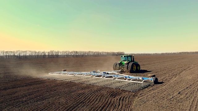 大轮犁上的农业耕作拖拉机鸟瞰图，在肥沃的农田上耙土，在翻耕过的土地上扬起巨大的尘土，准备播种。春季土壤耕作视频素材