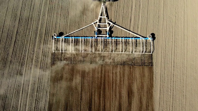 大轮犁上的农业耕作拖拉机鸟瞰图，在肥沃的农田上耙土，在翻耕过的土地上扬起巨大的尘土，准备播种。春季土壤耕作视频素材