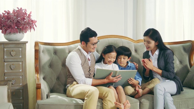 亚洲母亲和父亲读书与儿子和女儿在家里视频素材