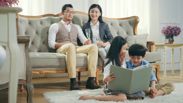 两个亚洲孩子在家里看书，有父母的背景视频素材