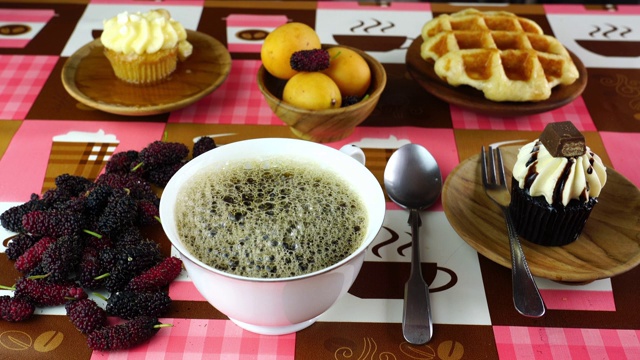 将黑咖啡倒入白色杯中，搭配各种甜品和热带水果视频素材