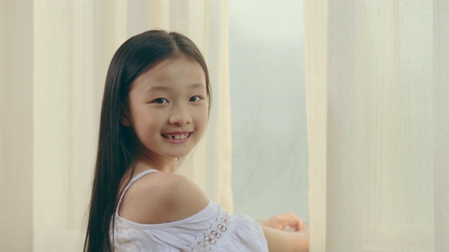 一个亚洲小女孩在卧室里看着窗外视频下载