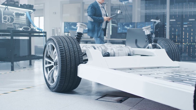 真正的电动汽车平台底盘原型概念站在高科技工业机械设计实验室。混合车架包括轮胎，悬挂，发动机和电池。视频素材