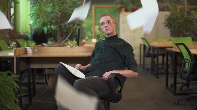 英俊的年轻人坐在现代绿色生态办公椅上视频素材