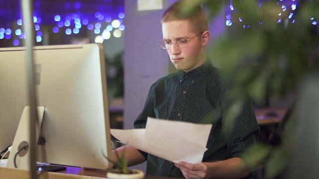 戴眼镜的年轻人坐在新电脑前扔纸视频素材