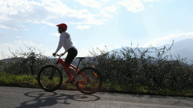 年轻女子骑着自行车经过橄榄园视频下载