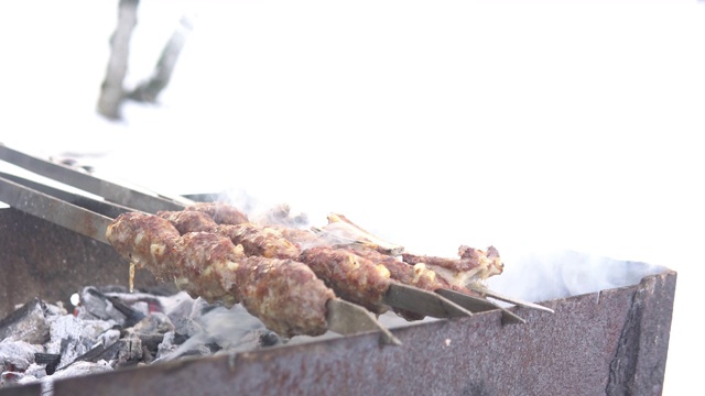 一个男人的手正在做西施露勒烤肉串。冬天或下雪时，在木炭烤架上煎肉。视频素材
