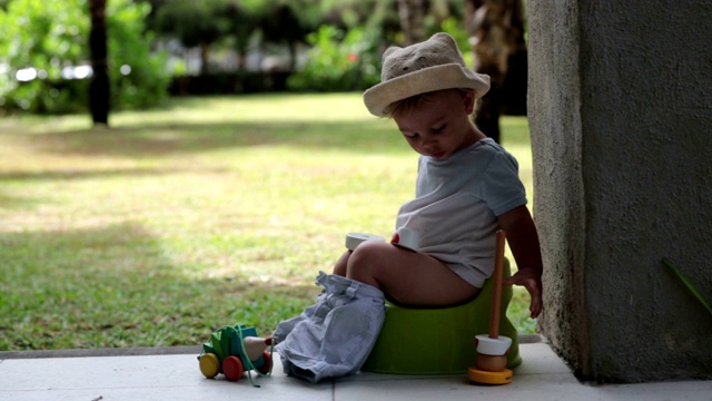 可爱的蹒跚学步的小男孩，正坐在度假胜地庭院的后门廊上，玩着玩具视频下载