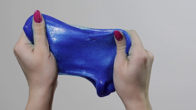 女人的手玩着奇怪的令人满意的蓝色黏液粘稠的物质。反应力的视频素材