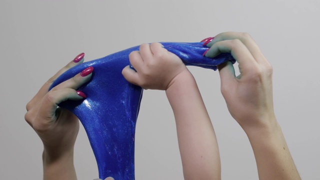 女人和孩子的手玩令人满意的蓝色粘液粘稠的物质。反应力的视频素材