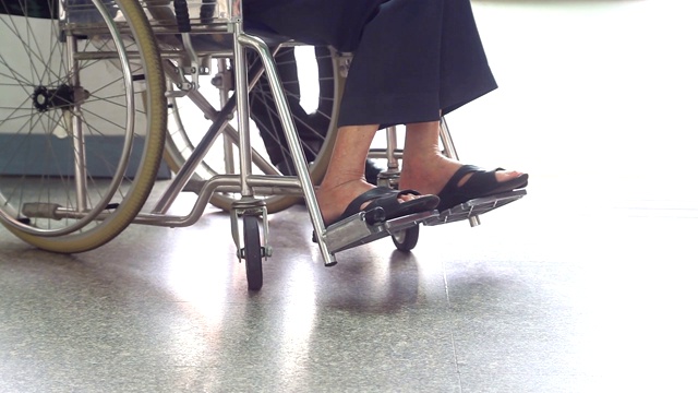 一个坐在轮椅上的病人的腿部特写。视频下载