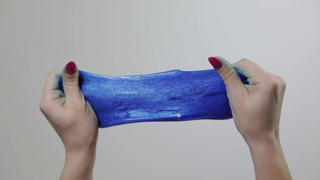 女人的手玩着奇怪的令人满意的蓝色黏液粘稠的物质。反应力的视频素材