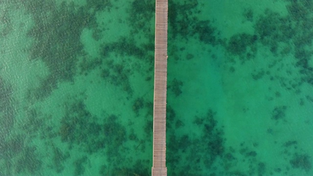 清澈的绿松石海洋与长木码头在日出，空中俯瞰视频下载