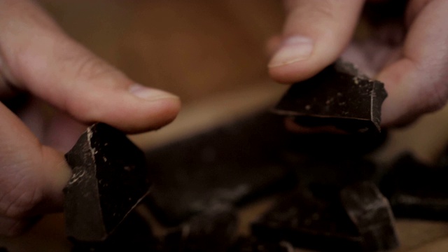 男人打碎了巧克力棒。缓慢的运动。关闭了。用手掰开一块巧克力。特写镜头。视频素材