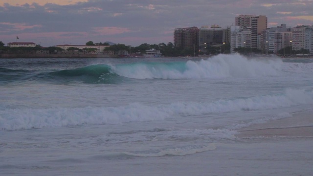 慢镜头:海浪与高层建筑在背景中破碎视频素材