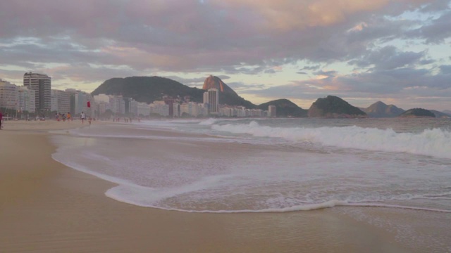 慢镜头:海水冲刷着海滩，后面是标志性的科帕卡巴纳海岸线视频素材
