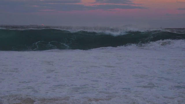 慢镜头:海浪在蓝色的海洋中形成和破碎，上面是粉红色的天空视频素材