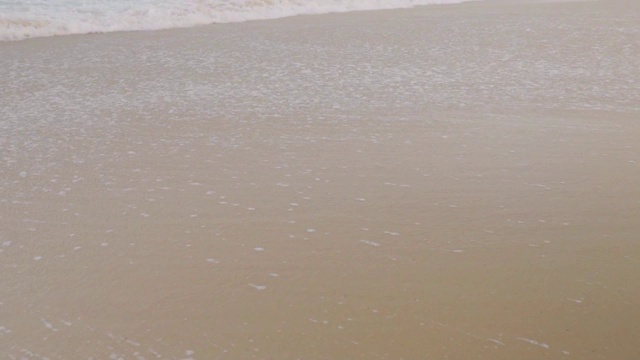 慢镜头:潮湿的沙滩，海水退去，新浪潮到来视频素材
