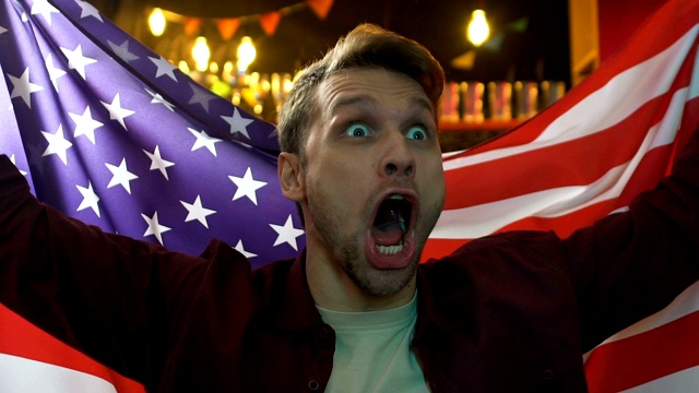 非常高兴的男球迷挥舞着美国国旗，庆祝国家队的胜利视频素材
